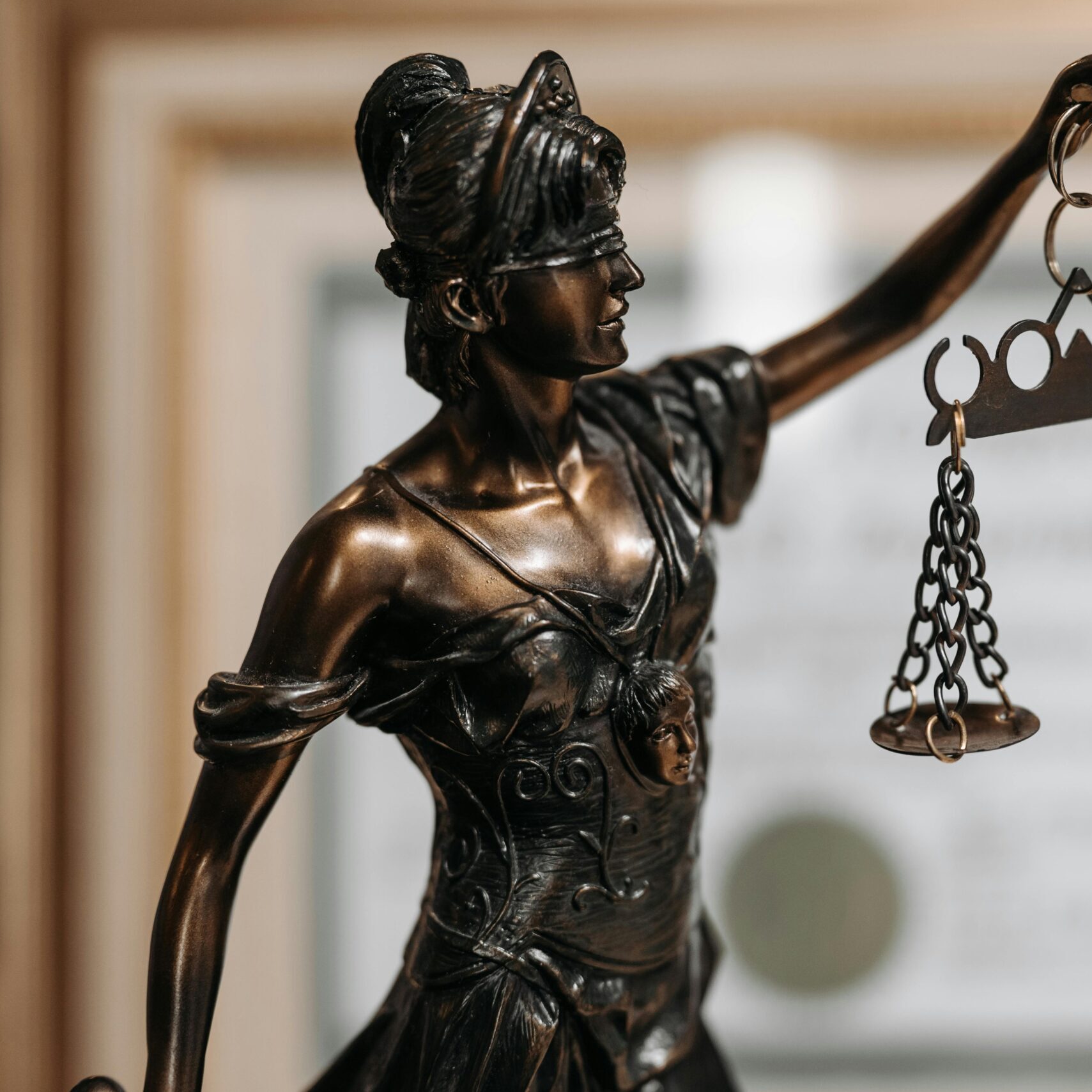 Close-up of a bronze Lady Justice statue holding scales in an office environment.