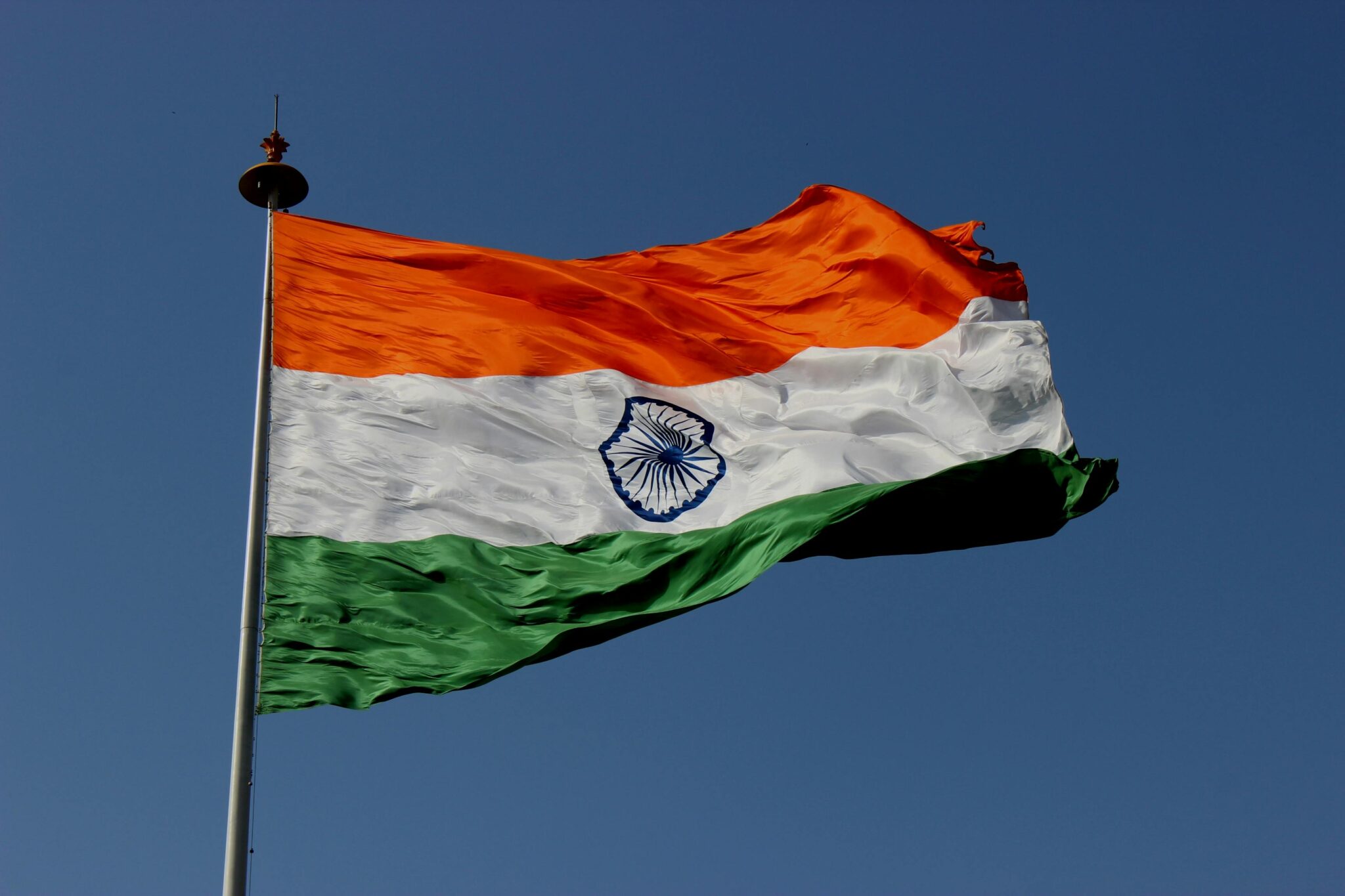 The Indian national flag waves proudly against a clear blue sky, symbolizing unity and pride.